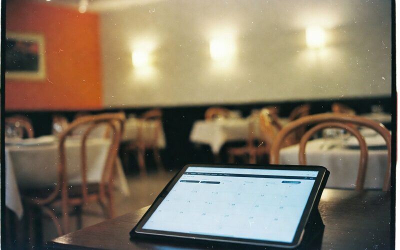 Tablette affichant un calendrier de réservations sur une table de restaurant dressée